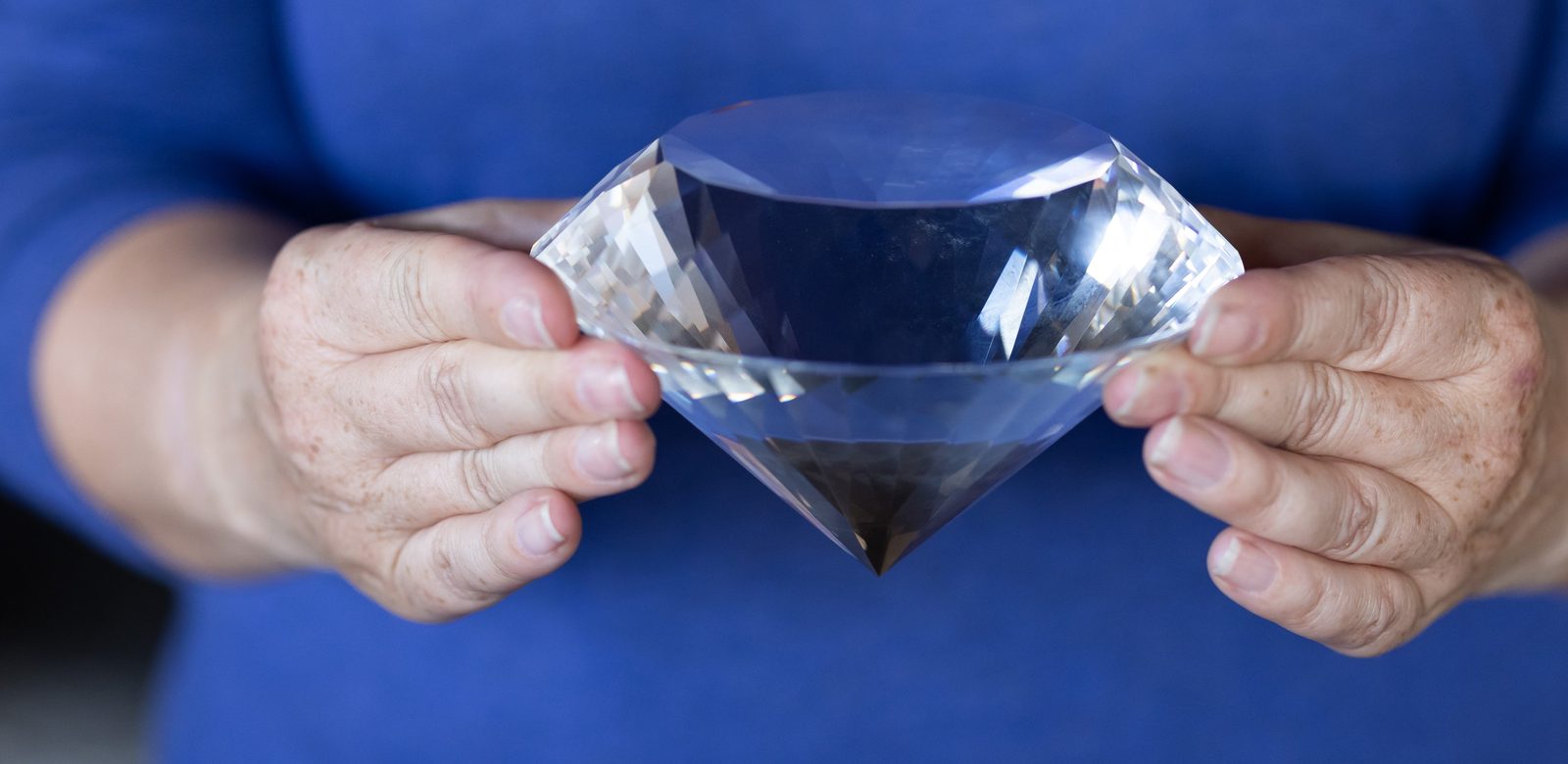 Hands holding a large cut diamond, representing the diamond-strong work of the DMC Service team
