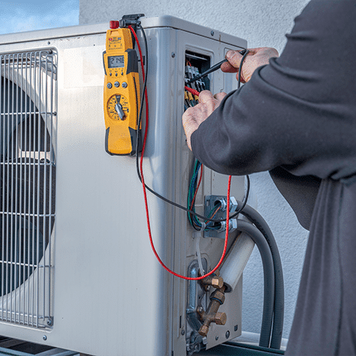 DMC Service technician testing electric components on HVAC system