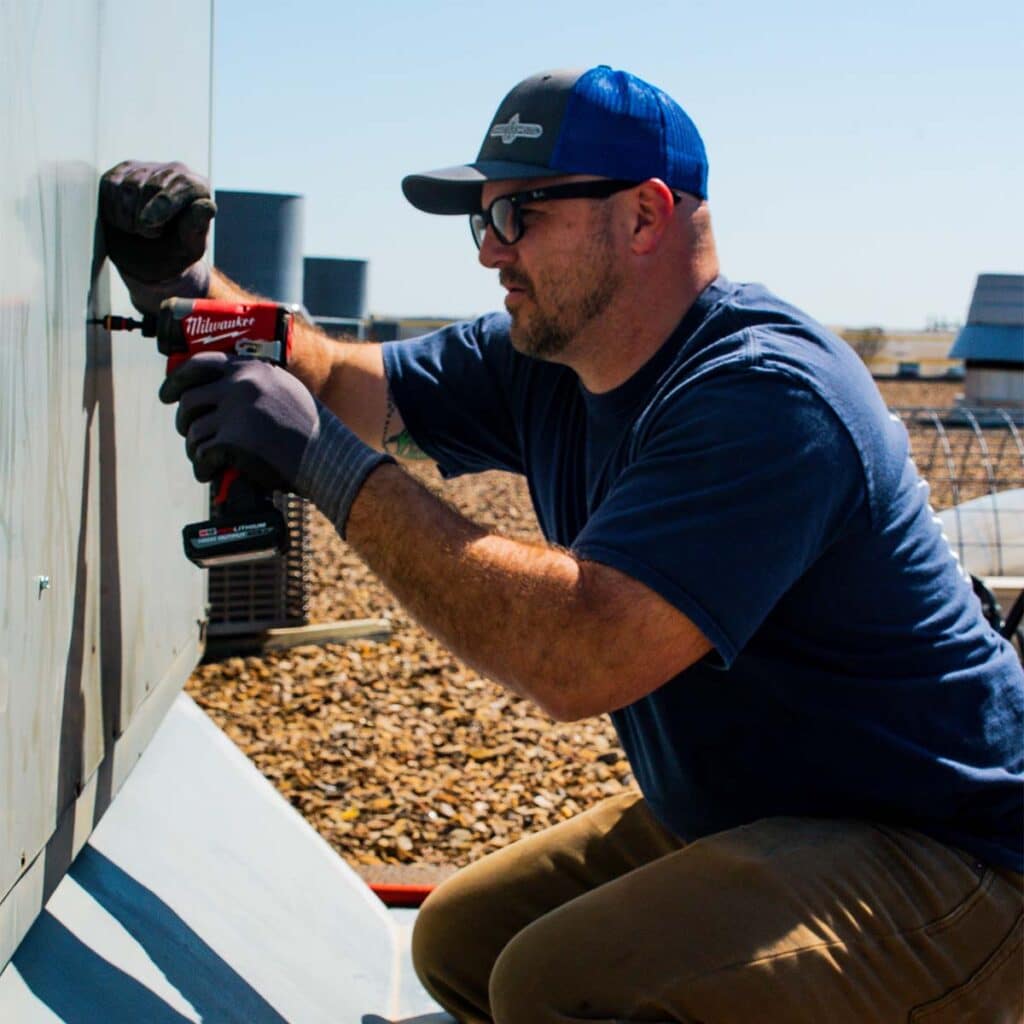 DMC technician installing a rooftop unit on a commercial building